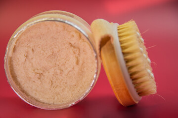 Organic body scrub displayed in a glass jar with a wooden brush, emphasizing natural ingredients and promoting skincare routines for beauty and wellness enthusiasts