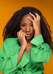 Confident black woman with curly hair posing against orange background