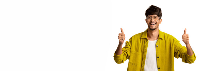 A young man stands confidently, smiling widely while giving two thumbs up. He wears a bright yellow...