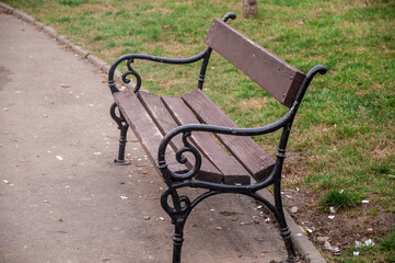 Empty park bench on sidewalk in public park
