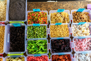 Colorful dried fruits and candies in containers at market
