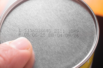 a man points his finger at the production date on a tin can