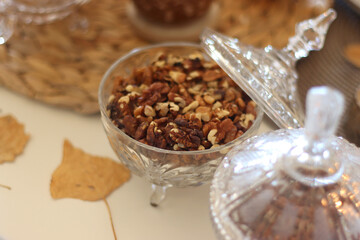 Lit candles, cookies, chocolate, nuts, tea, wine, pumpkins, books, reading glasses and autumn leaves on the table. Autumnal hygge at home. Selective focus.