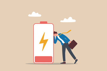 Businessman tired and exhausted, leaning on a low battery symbol.