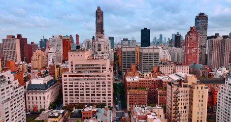 Flying over urban landscape of New York at dusk time. Cloudy overcast sky at backdrop. - Powered by Adobe