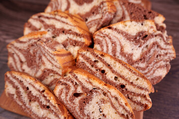 close-up of sliced marble cake revealing intricate chocolate and vanilla swirls atop a wooden surface, showcasing a delicious and inviting baked dessert presentation, traditional, handmade, golden