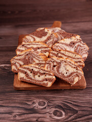 close-up of sliced marble cake with chocolate and vanilla swirls on wooden board against rustic wooden background creating a warm, homely atmosphere, aesthetic, enticing, moist, gourmet, culinary