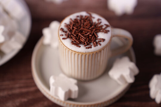 cozy coffee scene with ceramic mug topped with chocolate sprinkles and accompanied by snowflake-shaped marshmallows on a rustic wooden surface, creating a warm rustic atmosphere, pleasant, indulgent