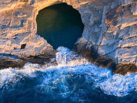  Top-down aerial of Giola&rsquo;s natural rock pool carved in golden limestone above the Aegean. Ideal for: Greece travel campaigns, adventure tourism, coastal geology features. Colours: teal, blue, sand.