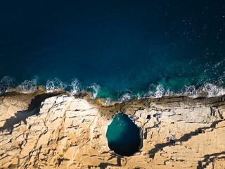 Top-down drone of Giola rock pool on Thassos with swimmers and a fresh splash in emerald water. Ideal for: Greece travel, adventure tourism, summer campaigns, social ads. Colours: teal, blue, beige. © Martin Mecnarowski