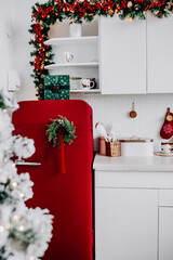 Festive kitchen featuring a red refrigerator, a pine cone wreath, red ornaments, creating a warm holiday atmosphere. Selective focus