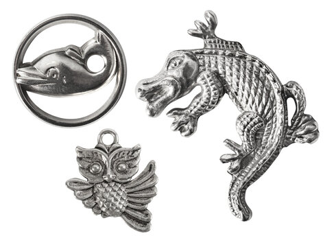 Isolated photo of various shaped silver colored animal pendants on white background.