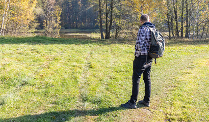 Man with a backpack is standing in a grassy field