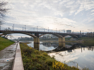 Fototapeta premium Bridge spans a river with a reflection of the sky in the water