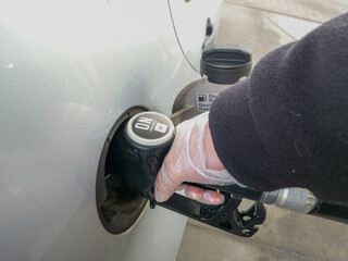 Hand refueling a diesel car with fuel pump nozzle at gas station.