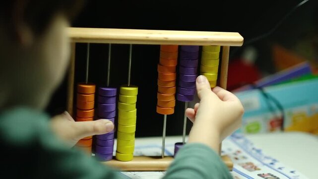 A child's hands use a colorful wooden abacus to count and learn mathematics. Montessori education concept.