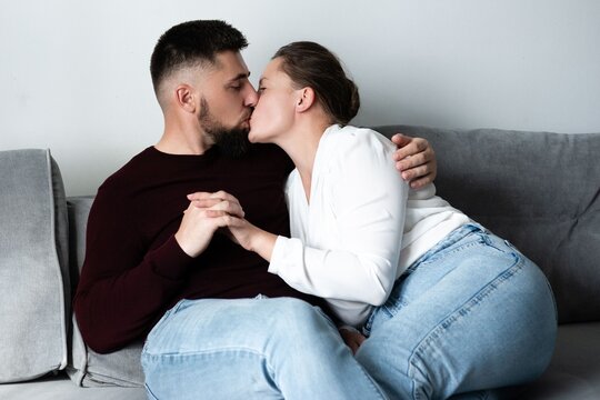 Intimate moment shared between two lovers cuddling on a cozy couch in their living room during a tranquil afternoon at home