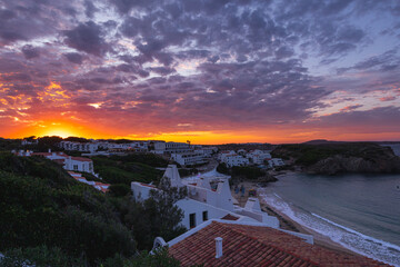 Stunning sunset over the bay of Arenal d'en Castell, Menorca. Vibrant colors reflected in the sea.