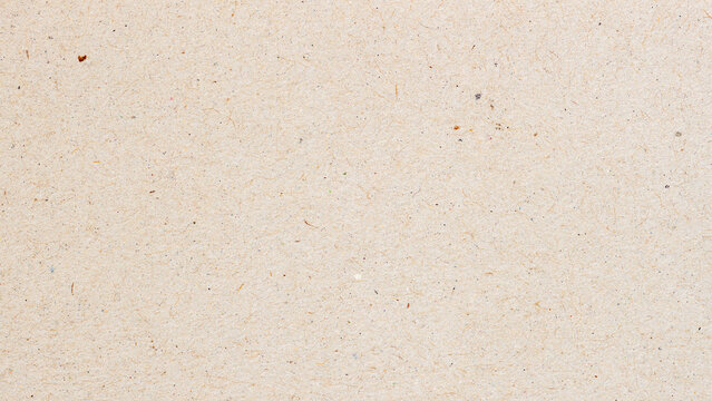 Macro of beige recycled craft paper with natural fiber and small colorful inclusions. Natural background for eco design, packaging or sustainable texture, copy space