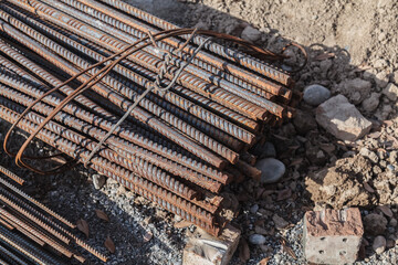 Pile of rusted iron bars on a rocky surface. The bars are twisted and bent, and they are scattered around the area. Scene is one of decay and abandonment, as the iron bars have been left to rust