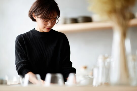 Asian cafe owner arranging drinks on the counter inside her warm cozy shop