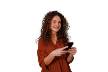 Woman with curly hair holding a smartphone, looking at camera and smiling on a transparent background