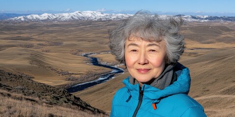 Woman smiling in blue jacket with mountainous Montana vista and river behind