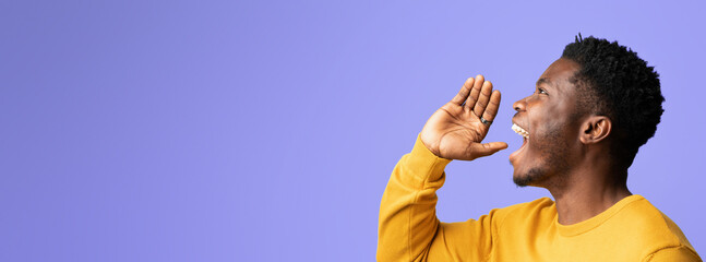 A man wearing a bright yellow sweater is excitedly shouting with a joyful expression. He stands...