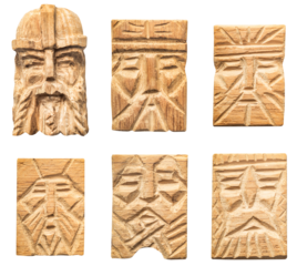 Isolated photo of wood carved scandinavian viking style face inlays, pendants or decorative elements on white background.