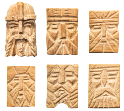 Isolated photo of wood carved scandinavian viking style face inlays, pendants or decorative elements on white background.