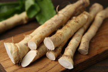 Fresh raw horseradish roots and leaves on wooden table, closeup