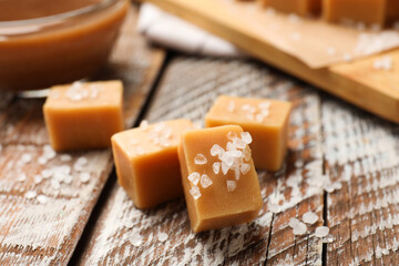 Tasty caramel candies with salt on color wooden table, closeup