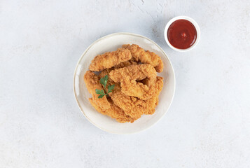 Crispy chicken strips with ketchup on a white background. Top view. Fast food.