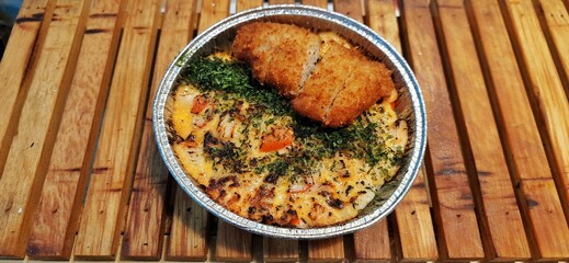Crispy Chicken Katsu and Salmon with Japanese Mentai Rice Sauce Dish Served in a Foil Container on Wood. Food Photography Presentation