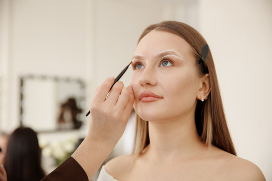 Young caucasian female receiving eyebrow tinting and correction in beauty salon