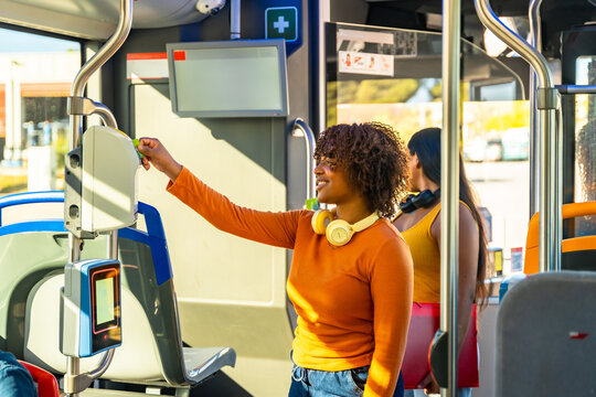 Young woman paying bus fare using validator