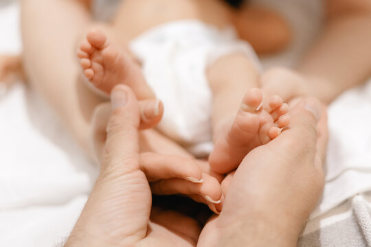Caucasian newborn baby feet gently held by adult hands - Powered by Adobe