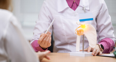 Female doctor Neurologist osteopath explains shoulder anatomy using model in medical consultation