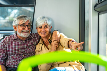 Senior couple traveling by bus pointing out window