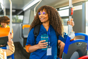 Black nurse commuting on public bus holding reusable cup © unai