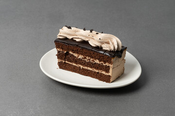 Chocolate cake slice with creamy frosting on a plate ready to be enjoyed