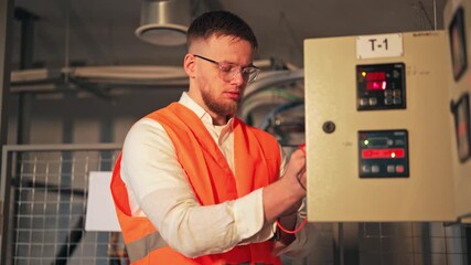 Dedicated engineer diligently checks electrical control panel systems. Focused on maintenance, ensuring reliable operation of complex equipment. Demonstrates concentration.