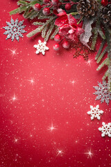 Christmas red vertical background with decorative poinsettia, fir branch, snowflakes and cones for tree decoraton. New Year winter holiday composition with decor and copy space, top view.