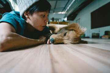 A real Asian man takes a selfie with a year-old golden retriever. The dog is licking its owner's face. Smiling People and fun playing together looking happily at the camera at home Pet and person