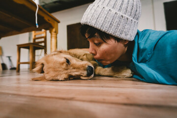 A real Asian man takes a selfie with a year-old golden retriever. The dog is licking its owner's face. Smiling People and fun playing together looking happily at the camera at home Pet and person
