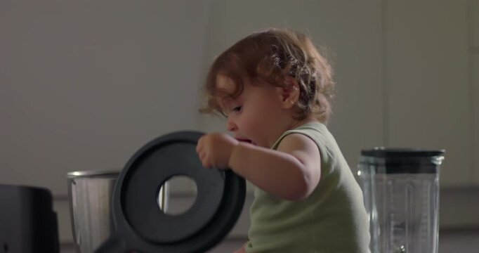 Toddler sitting on kitchen floor placing lid onto metal container with curious careful movement in simple everyday home moment
