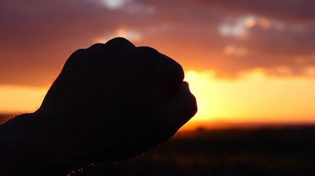 Silhouette hand framing the sun at sunset scenic golden hour natural lighting conceptual imagery