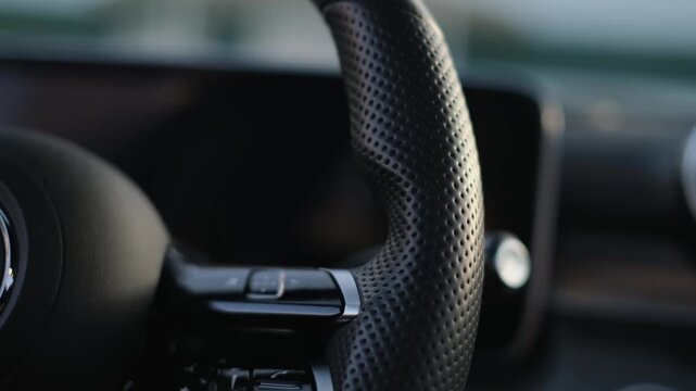 Close-up of a man's hand touching the texture of a perforated genuine leather steering wheel in a car
