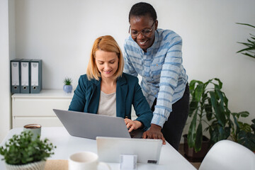 Diverse businesswomen collaborating efficiently on laptop in modern office