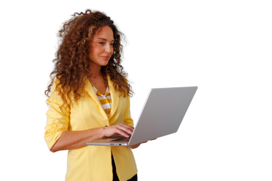 Woman with curly hair wearing a yellow blazer, standing and typing on a silver laptop, engaging in remote business work